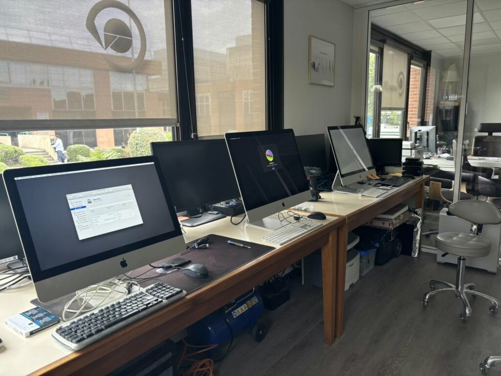 Rangée d'iMac en cours de traitement sur les postes de l'atelier de Labège